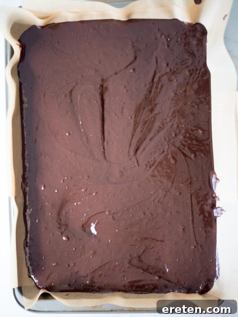 Close-up of rich, dark brownie batter smoothed evenly in a baking pan, ready to be baked into delicious Halloween treats.