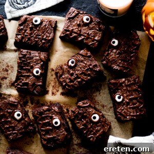 Main image for Halloween Brownies Recipe, showing a decorated brownie with a spooky theme next to a candle and pumpkin.