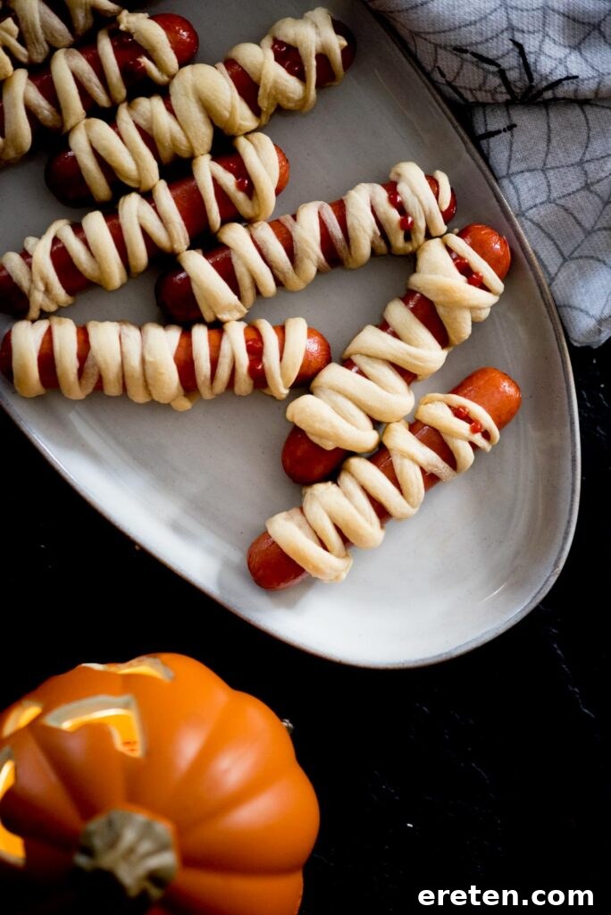 Halloweenie Mummies 2 Delicious and spooky mummy pigs in a blanket arranged on a serving tray, ready for a Halloween party
