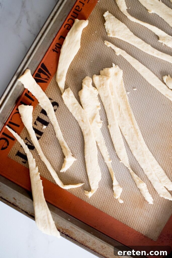 Halloweenie Mummies 4 Crescent roll dough cut into thin strips, ready for wrapping hot dogs