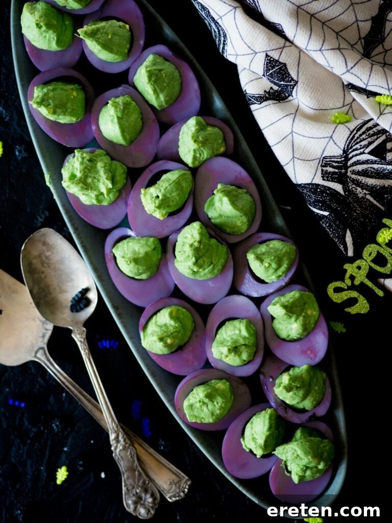 Halloween-themed deviled eggs arranged beautifully on a serving platter with Halloween decor