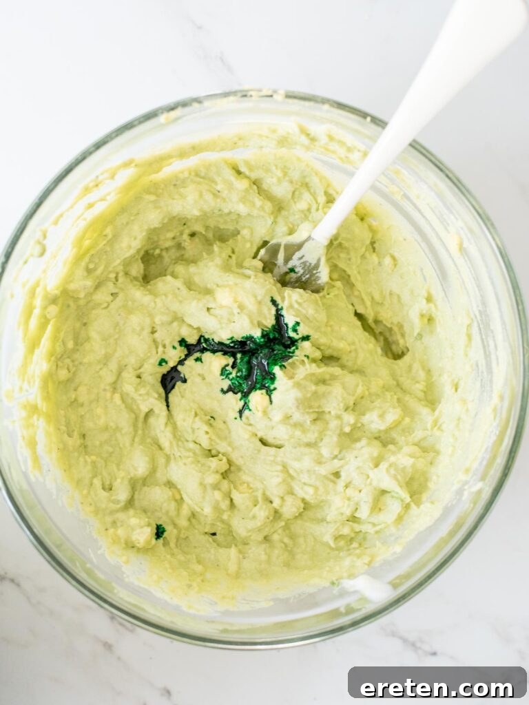 Green food coloring being dropped into the creamy egg filling mixture.