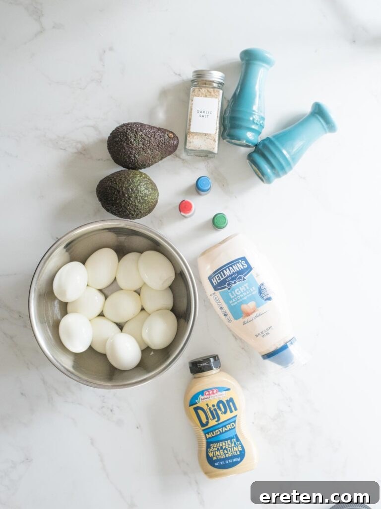 A selection of ingredients laid out for making Halloween deviled eggs, including eggs, avocados, mayo, mustard, and food coloring.