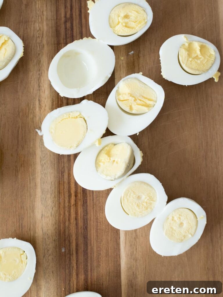 Freshly hard-boiled eggs on a wooden cutting board, ready for slicing.