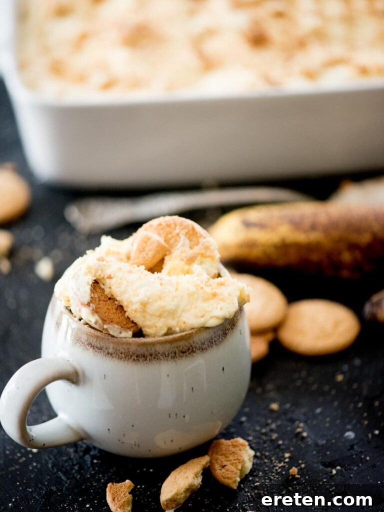 A delicious individual serving of homemade banana pudding in a mug, garnished with crushed vanilla wafers, ready to be enjoyed.