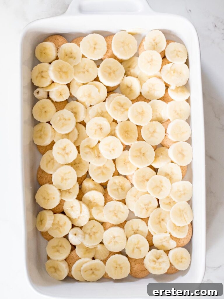 Freshly sliced bananas evenly spread over the layer of vanilla wafers in the casserole dish.