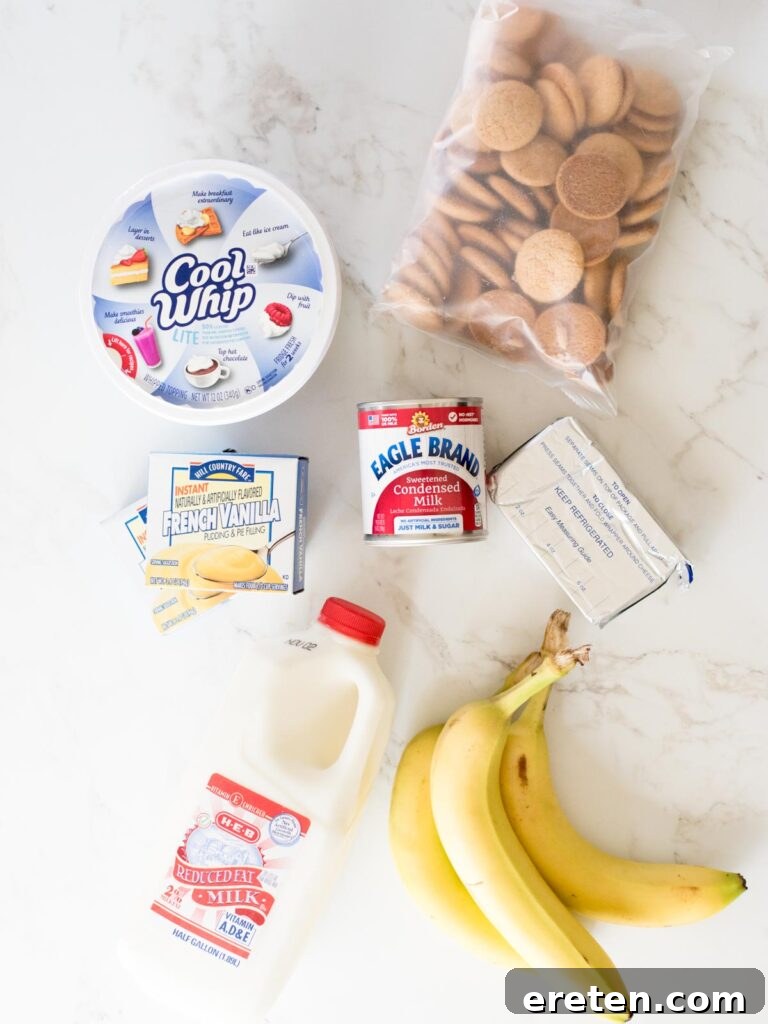 Fresh ingredients laid out on a wooden surface, including milk, instant pudding mix, cream cheese, sweetened condensed milk, cool whip, vanilla wafers, and bananas, ready for making homemade banana pudding.