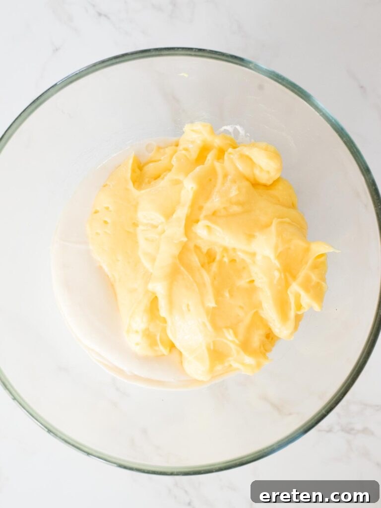 The instant pudding mixture being carefully added to the cream cheese and sweetened condensed milk mixture.