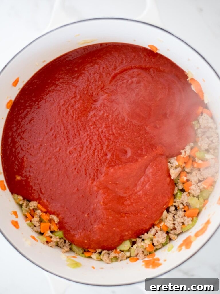 Quick and Comforting Pasta Fagioli 9 crushed tomatoes and tomato sauce added to dutch oven with sausage mix