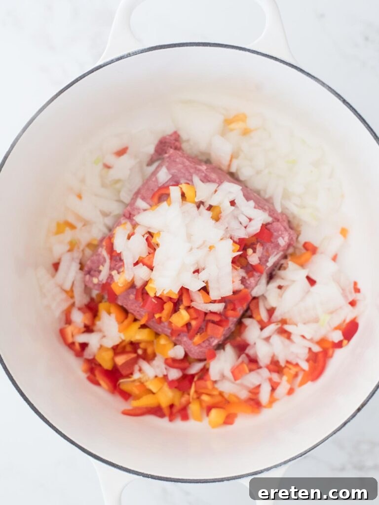 Finely chopped onion joining the bell peppers and ground beef, beginning to soften and release its aromas.