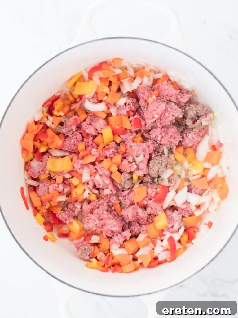 The beef and vegetable mixture thoroughly combined and cooking down in the Dutch oven, absorbing the spices.